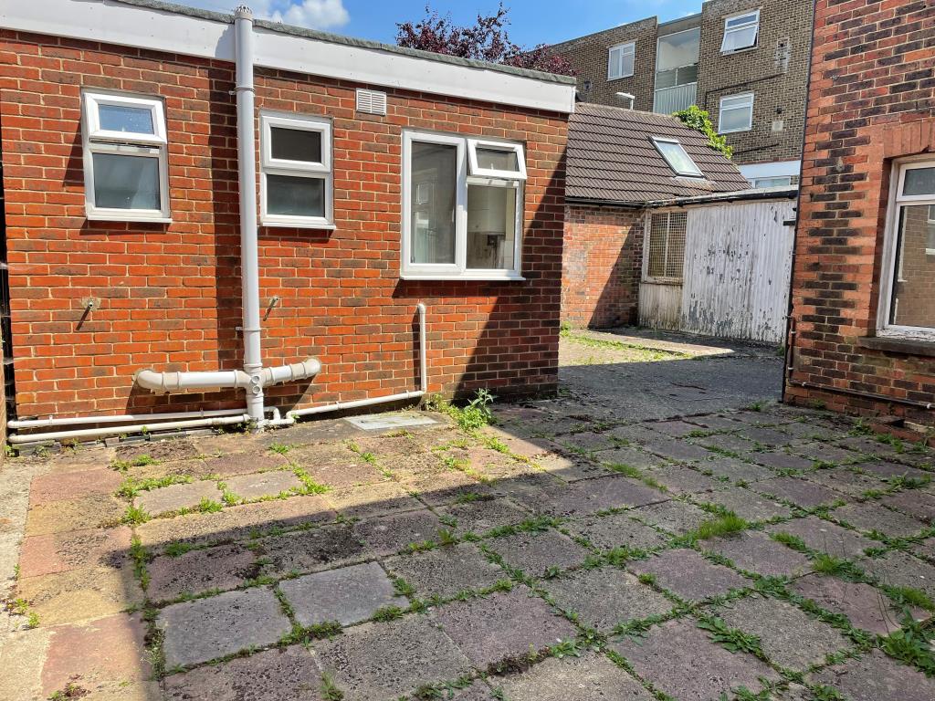 Lot: 139 - RETAIL UNIT AND WORKSHOP WITH GARAGE AND TWO FLATS - View of paved courtyard area from garage